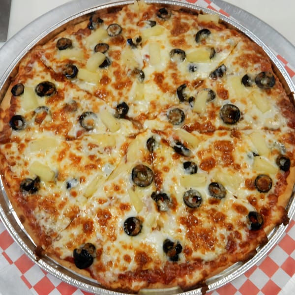 A whole Cerello's Pizza with pineapple and black olives, sliced and ready to eat.