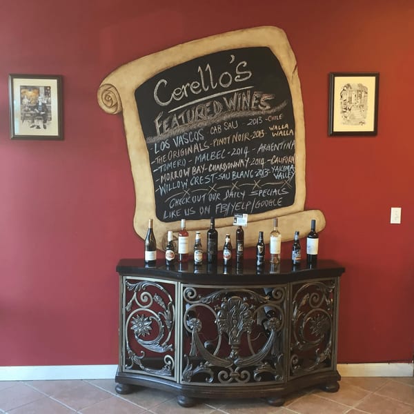 Cerello's featured wines chalkboard menu above a decorative console table with wine and beer bottles.